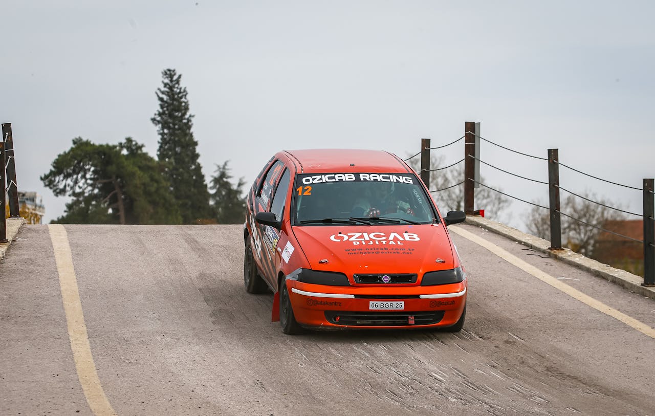 A red Fiat Palio racing car from Ozicab Racing on an outdoor track, showcasing motorsport action.