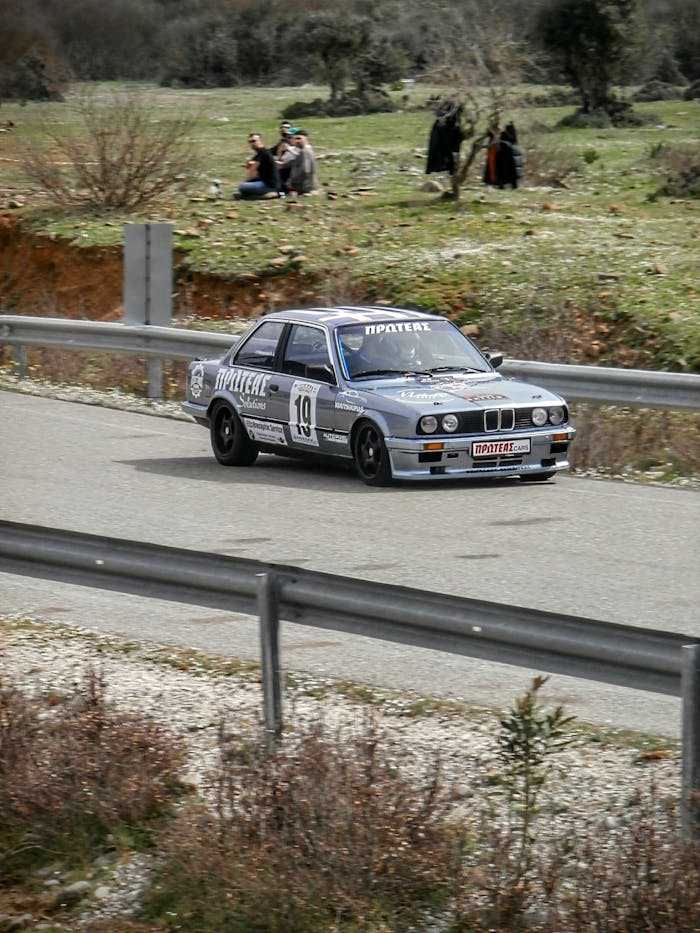 services-02 Vintage race car speeding down a scenic road with spectators enjoying the dynamic event.