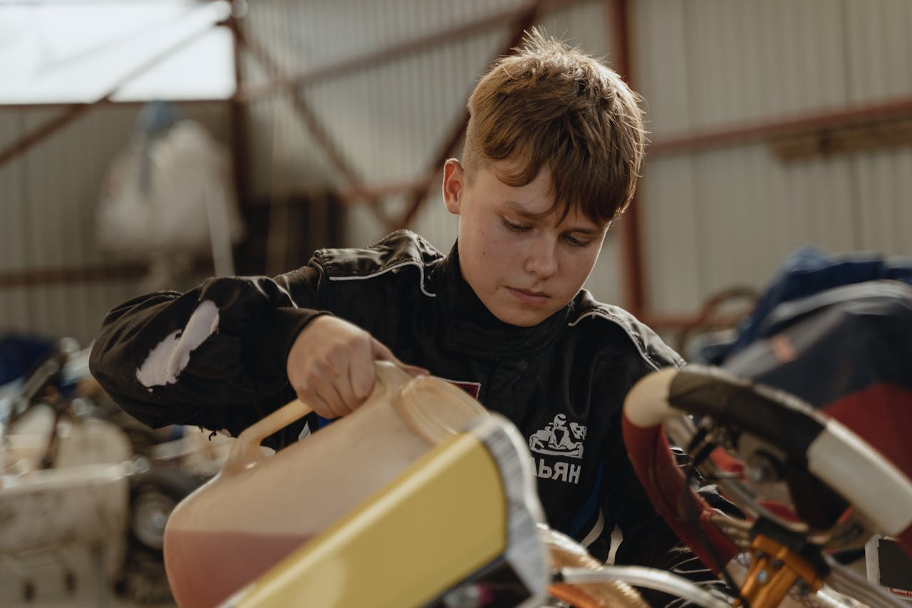 services-bg A young boy refuels a racing kart indoors, preparing for competition.